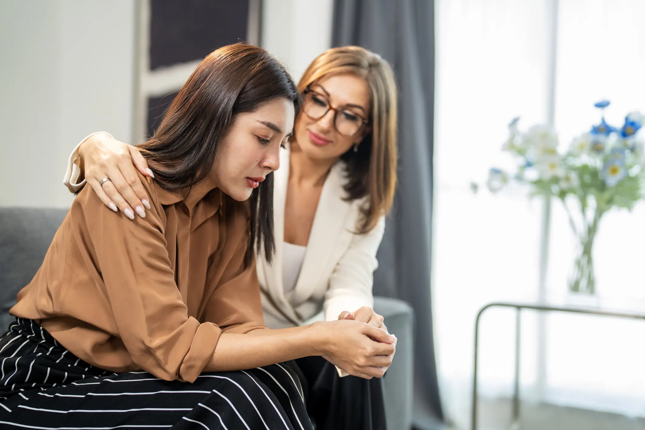 Woman Comforting Another in an Emotional Moment Indoors on a Couch